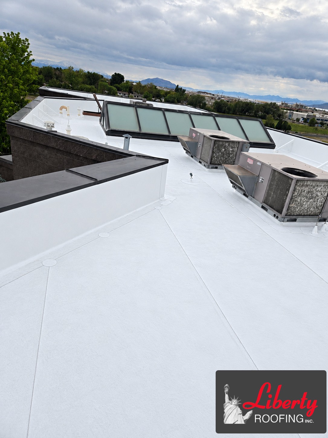 Completed commercial TPO roof replacement in Pleasant Grove with skylight and rooftop HVAC units