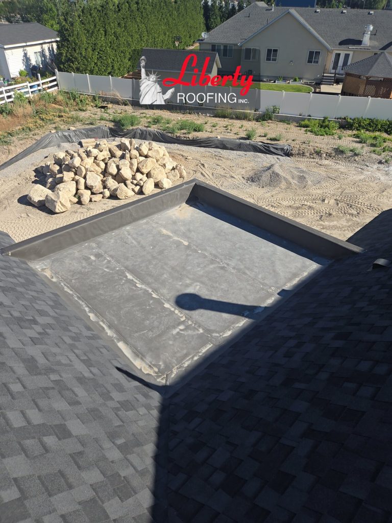 Small TPO membrane roof section bordered by shingles and raised perimeter edges on an American Fork home