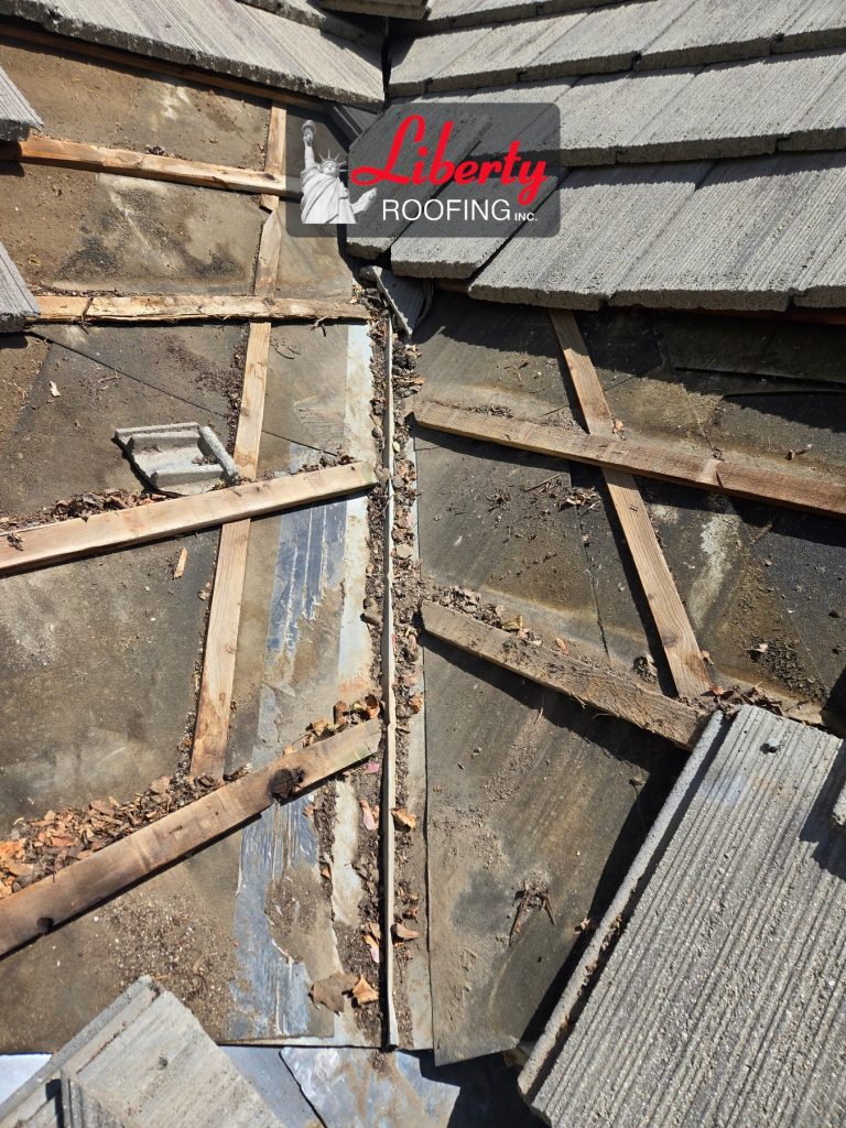 Exposed underlayment, battens and old metal flashing in a leaking concrete tile roof valley in Provo